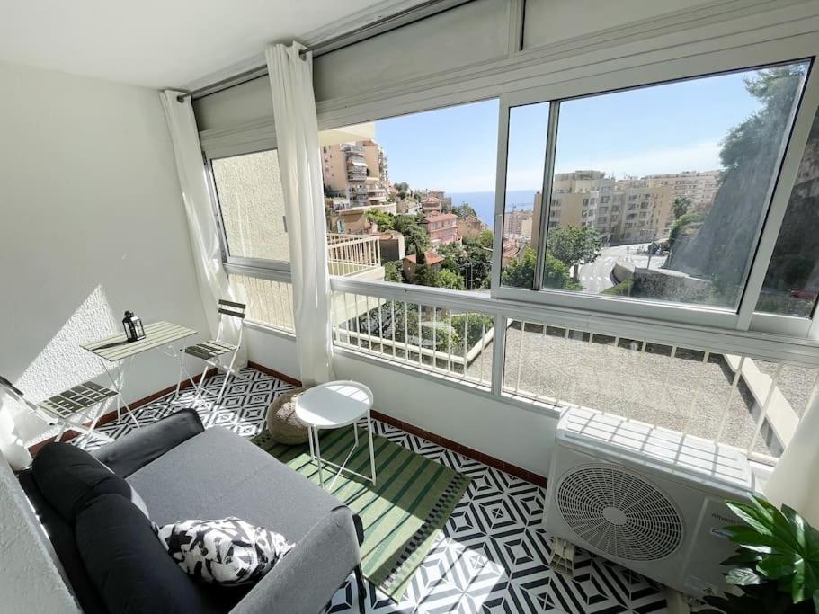 un salon avec un canapé et une grande fenêtre dans l'établissement Le guynemer, à Beausoleil