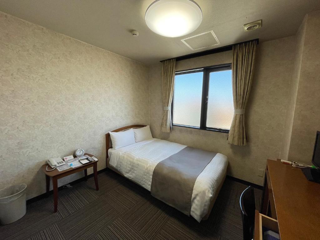 a hotel room with a bed and a window at Shinmatsudo Station Hotel in Matsudo