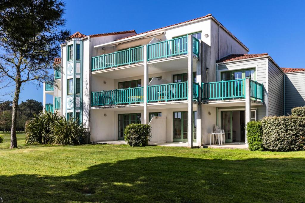 un immeuble d'appartements avec des balcons verts et une cour dans l'établissement Résidence Port Bourgenay - maeva Home - Appartement 2 pièces 4 personnes - Sélection MAE-0434, à Talmont-Saint-Hilaire