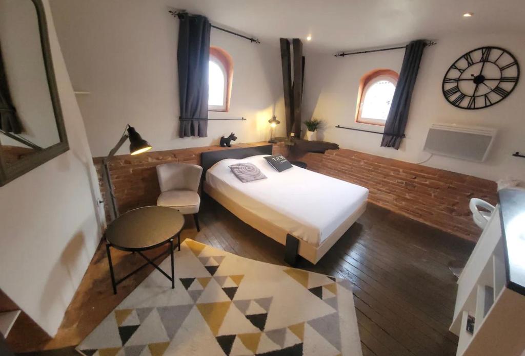 1 dormitorio con 1 cama y reloj en la pared en Le Colombier - A deux pas du square Charles de Gaulle, en Toulouse