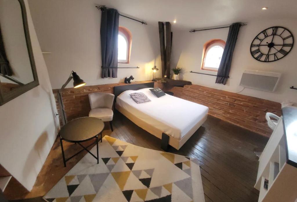 une chambre avec un lit et une horloge au mur dans l'établissement Le Colombier - A deux pas du square Charles de Gaulle, à Toulouse