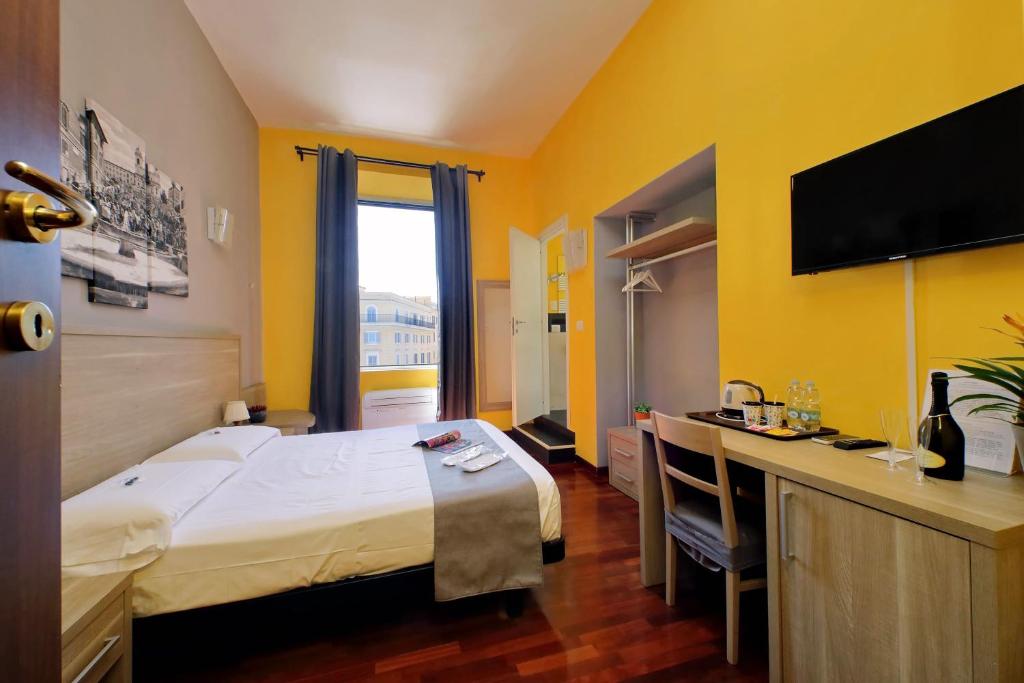 ローマにあるLHG Comfy Roomsの大きなベッドとデスクが備わるホテルルームです。