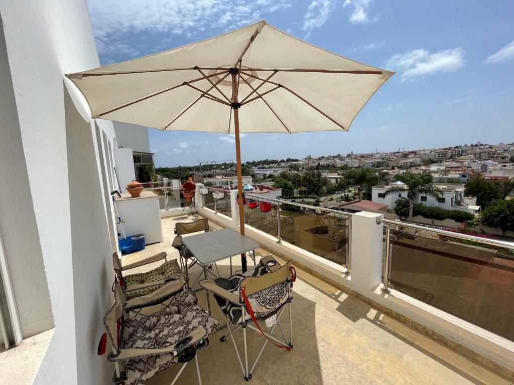 a patio with an umbrella and chairs on a balcony at Terrasse En Vue in Temara