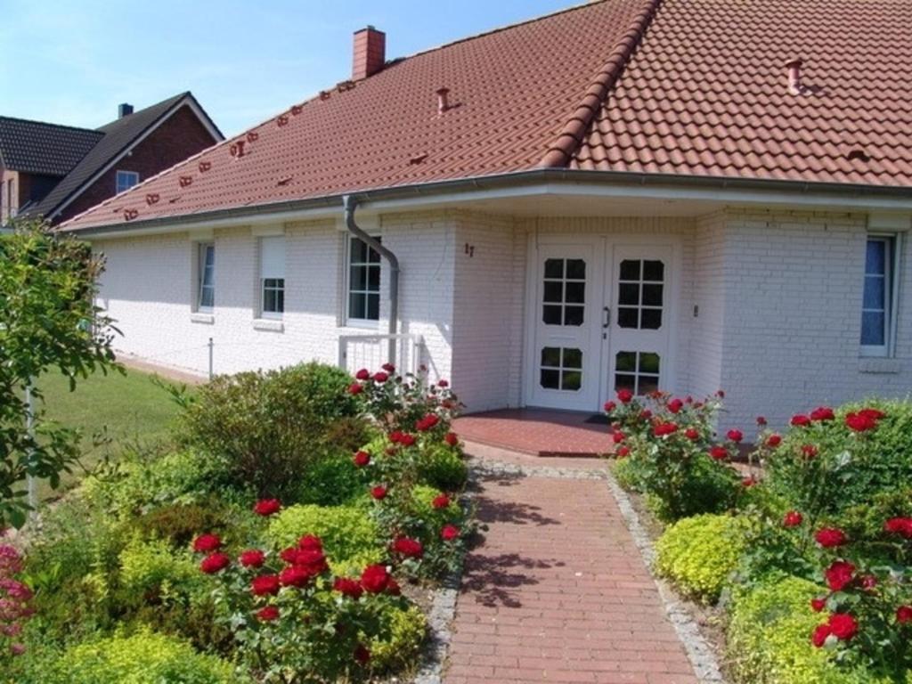 a white house with a red roof and some flowers at Ferienhaus Brombeerhof in Munkbrarup