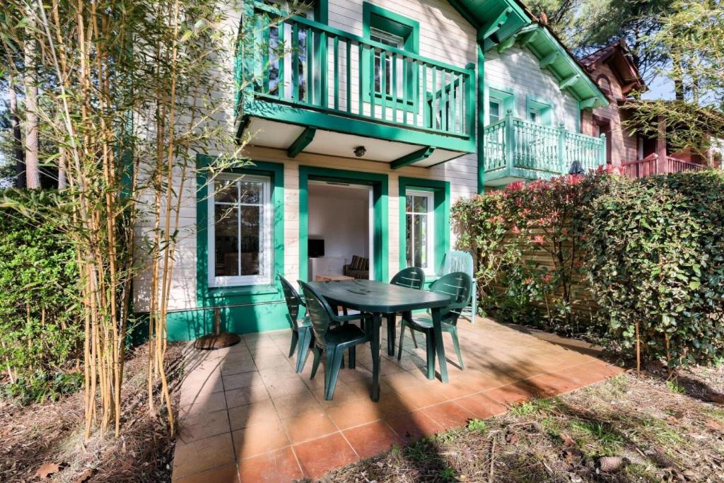 un patio avec une table et des chaises devant une maison dans l'établissement Les Maisons de Lacanau les Pins - maeva Home - Maison 3 pièces 8 personnes - Sélection MAE-7709, à Lacanau