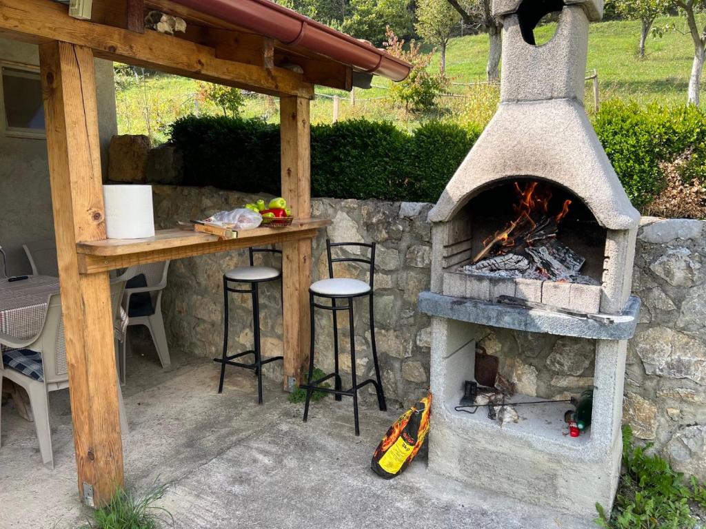 a stone oven with stools and a table with a fire at Vikendica Olivia 