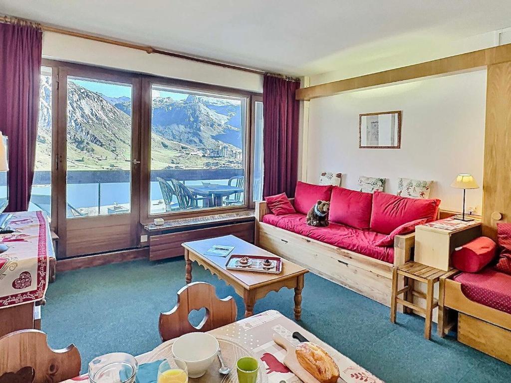- un salon avec un canapé rouge et une grande fenêtre dans l'établissement Studio skis aux pieds pour 4, proche commerces et balcon sud à Tignes - FR-1-411-440, à Tignes