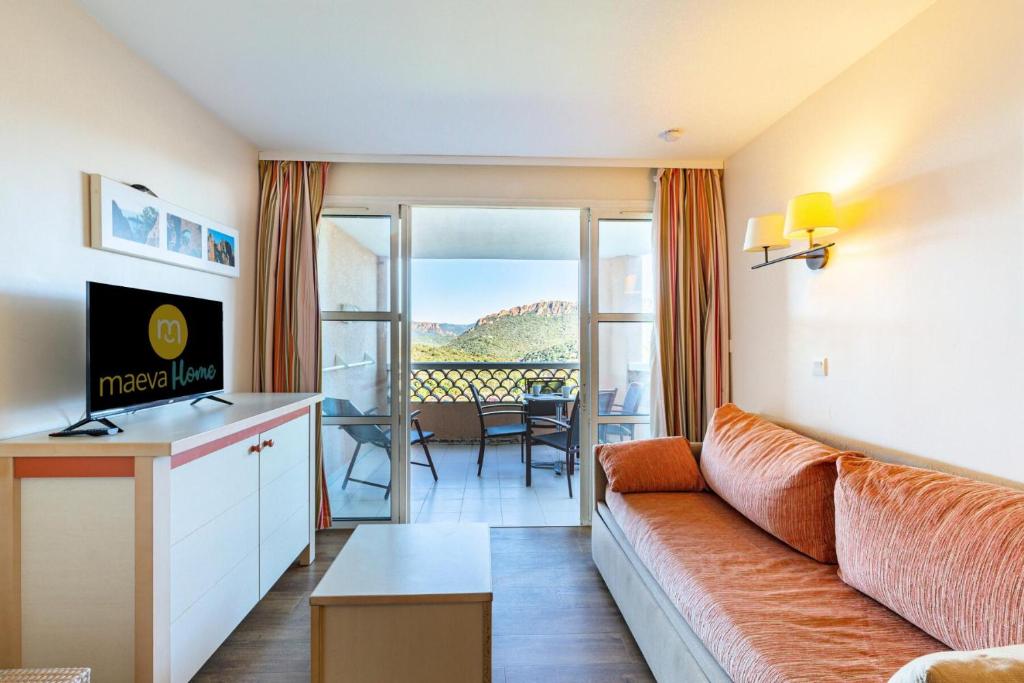 d'un salon avec un canapé et une vue sur un balcon. dans l'établissement Résidence le Village de Cap Esterel - maeva Home - Studio 4 personnes - Sélection MAE-4734, à Saint-Raphaël