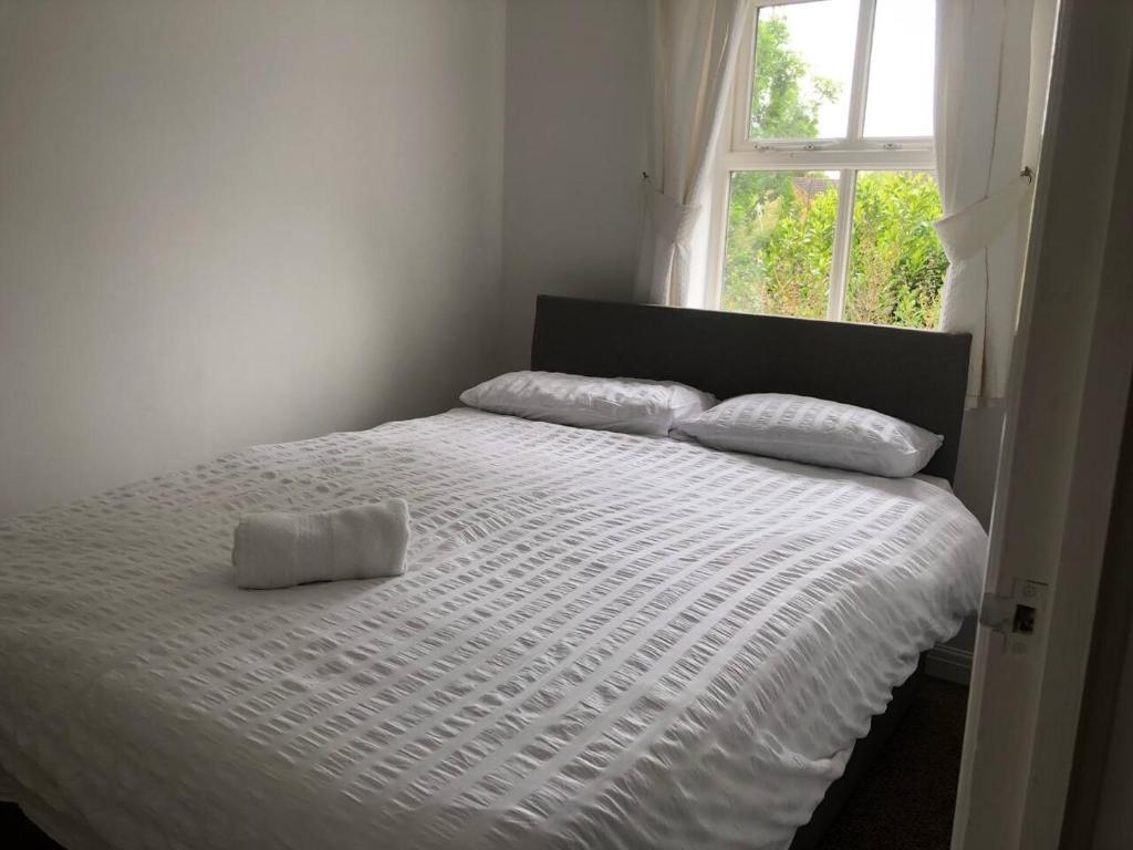a white bed with two pillows and a window at Bluebell House 2 bedroom with parking and garden in Scunthorpe