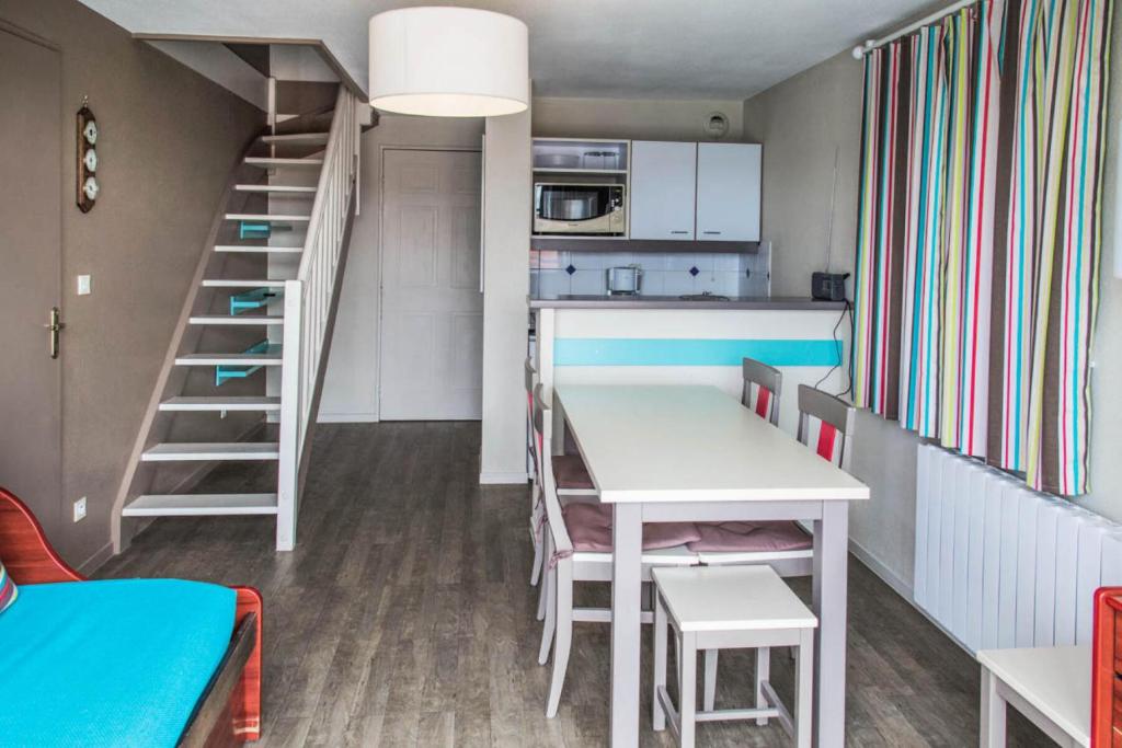 a kitchen and dining room with a table and a staircase at Résidence Port Guillaume - maeva Home - 3 Pièces 6 Personnes Sélection MAE-1552 in Dives-sur-Mer