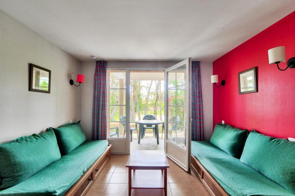 - un salon avec un canapé vert et des murs rouges dans l'établissement La résidence du Lac - maeva Home - Studio 5 Personnes - Sélection MAE-4214, à Monflanquin