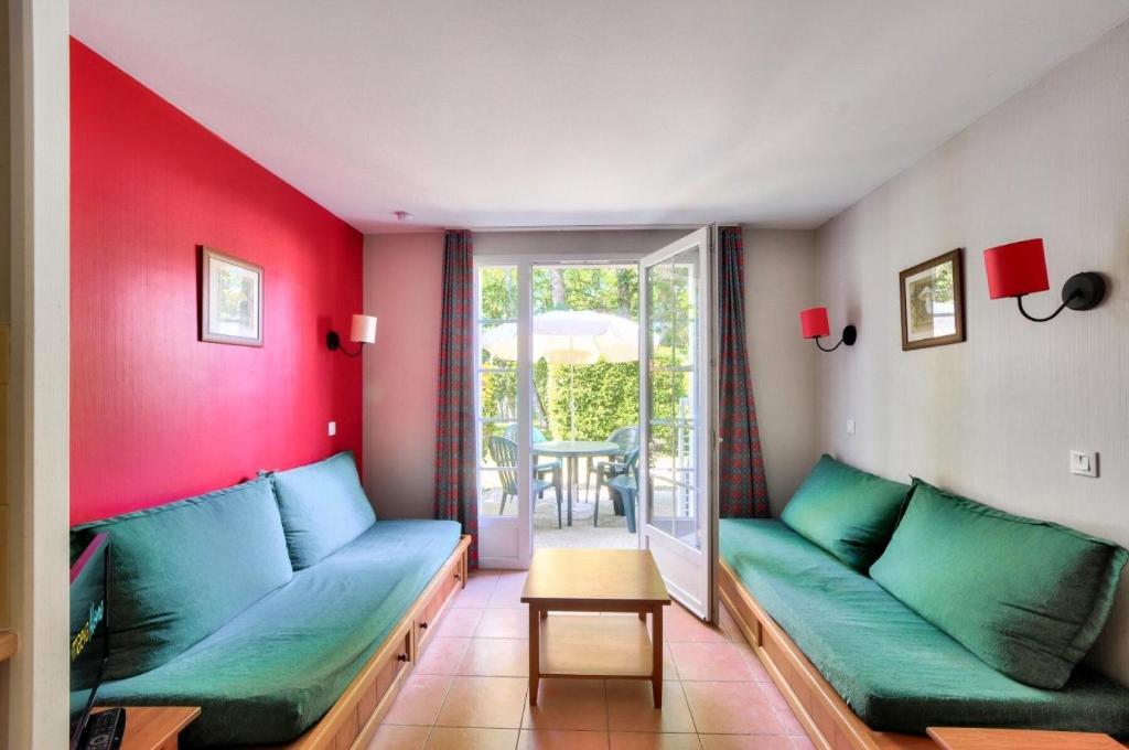 - un salon avec un canapé vert et des murs rouges dans l'établissement La résidence du Lac - maeva Home - Appartement 2 pièces 5 personnes - Confort MAE-4184, à Monflanquin
