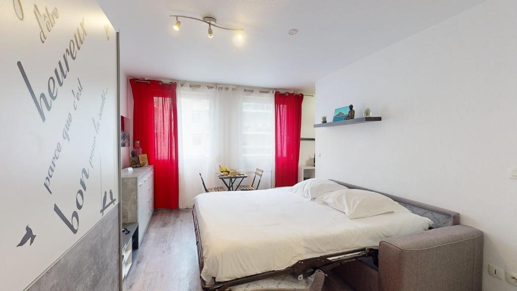 - une petite chambre avec un lit et des rideaux rouges dans l'établissement Studio Schilick, à Schiltigheim