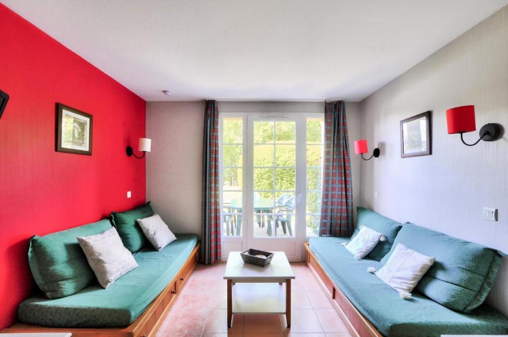 - un salon avec un canapé et un mur rouge dans l'établissement La résidence du Lac - maeva Home - Maison 2 pièces 5 personnes - Prestige MAE-4734, à Monflanquin