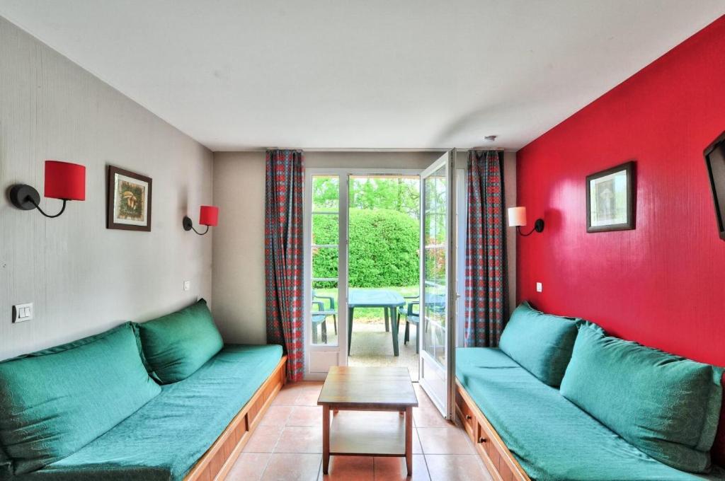 - un salon avec un canapé vert et des murs rouges dans l'établissement La résidence du Lac - maeva Home - Maison 2 pièces 5 personnes - Sélection MAE-4244, à Monflanquin
