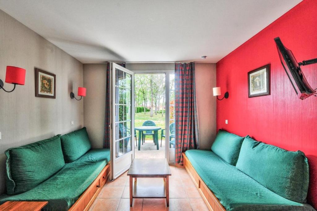 - un salon avec des canapés verts et un mur rouge dans l'établissement La résidence du Lac - maeva Home - Maison 2 pièces 5 personnes - Sélection MAE-4354, à Monflanquin
