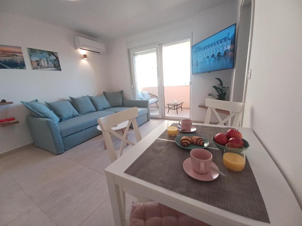 a living room with a table and a blue couch at Apartment Mare - lovely flat few steps away from the main bus station and Zadar old town in Zadar