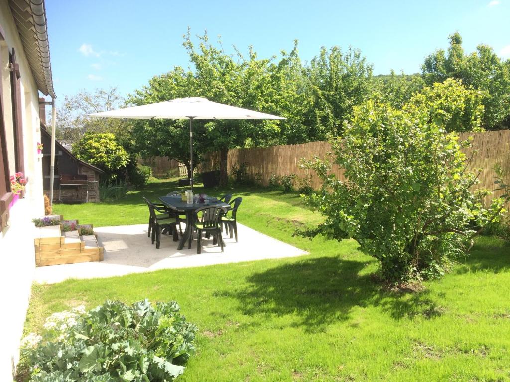 een patio met een tafel en een parasol in een tuin bij Le Galvani in Honfleur