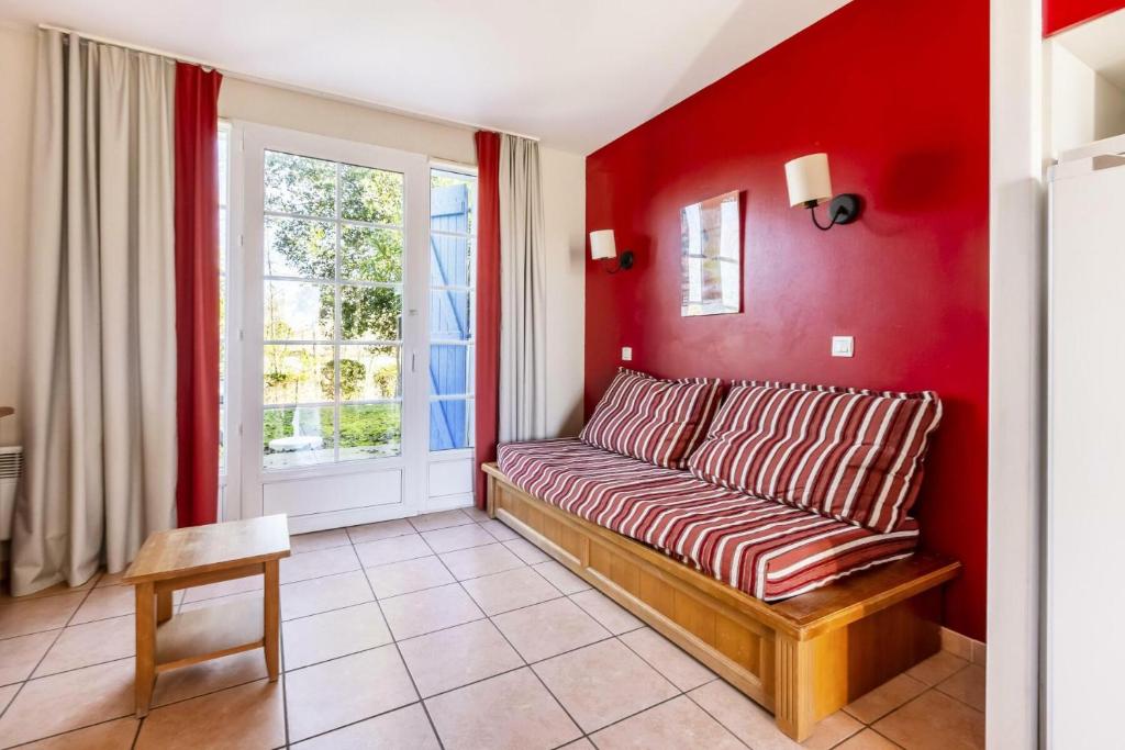 sala de estar de color rojo con sofá y ventana en Résidence Le Hameau du Lac - maeva Home - Maison 3 pièces 6 personnes - Co 364 en Marciac