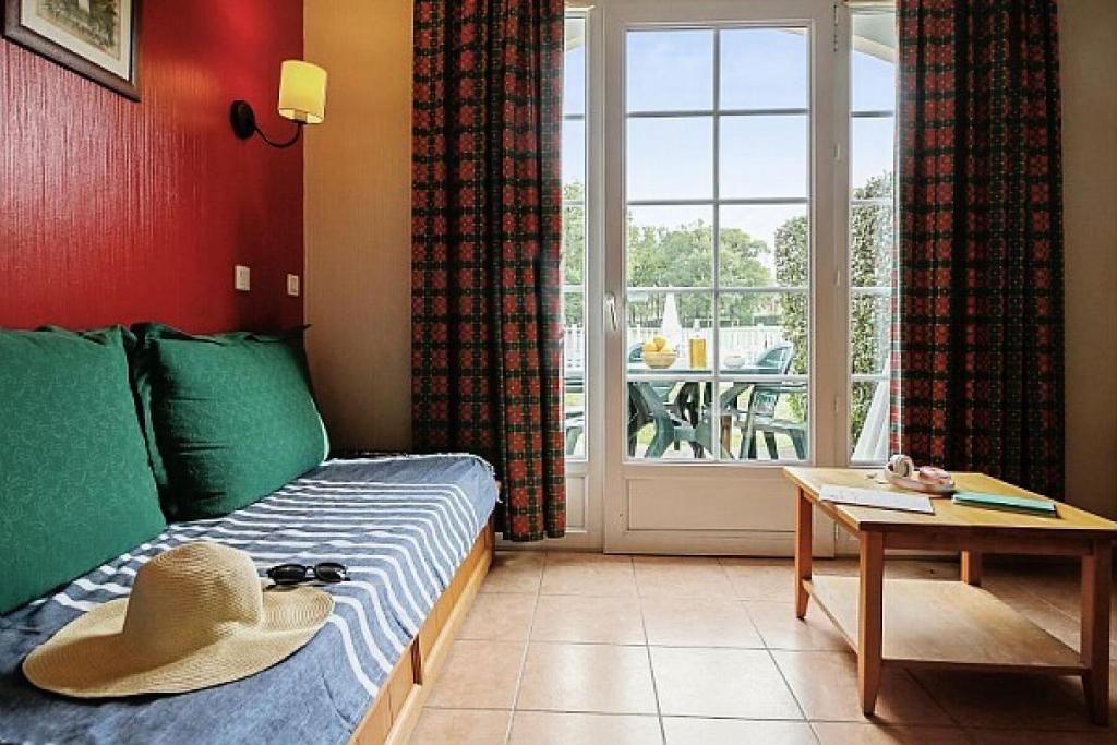 een hoed op een bed in een kamer met een raam bij La résidence du Lac - maeva Home - Appartement 2 pièces 5 personnes - Conf 694 in Monflanquin