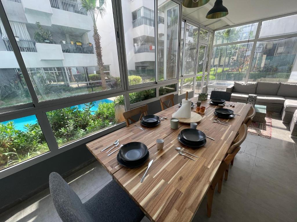 a wooden table in a room with a large window at Au Cœur Des Sables D’or - Harhoura in Temara