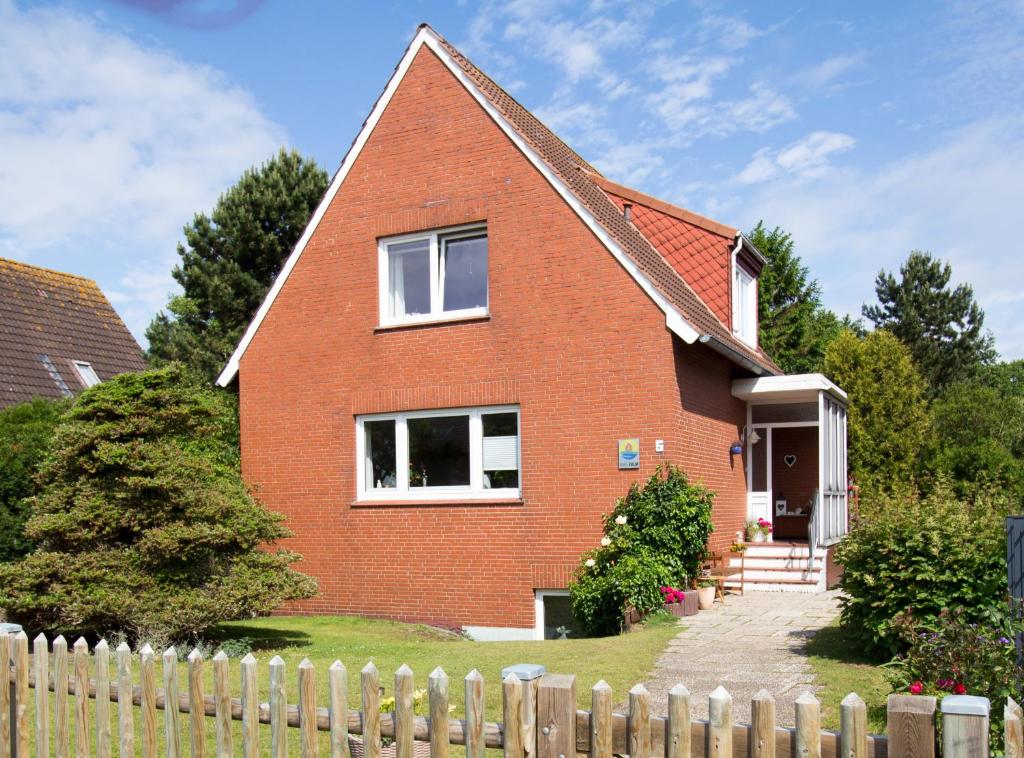 a red brick house with a wooden fence at Apartment Haus Julia in Norderney