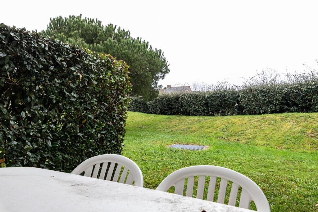 una mesa y sillas en un patio junto a un seto en Port du Crouesty Cap'Océan - maeva Home - Appartement 2 Pièces 4 Personnes 424, en Arzon