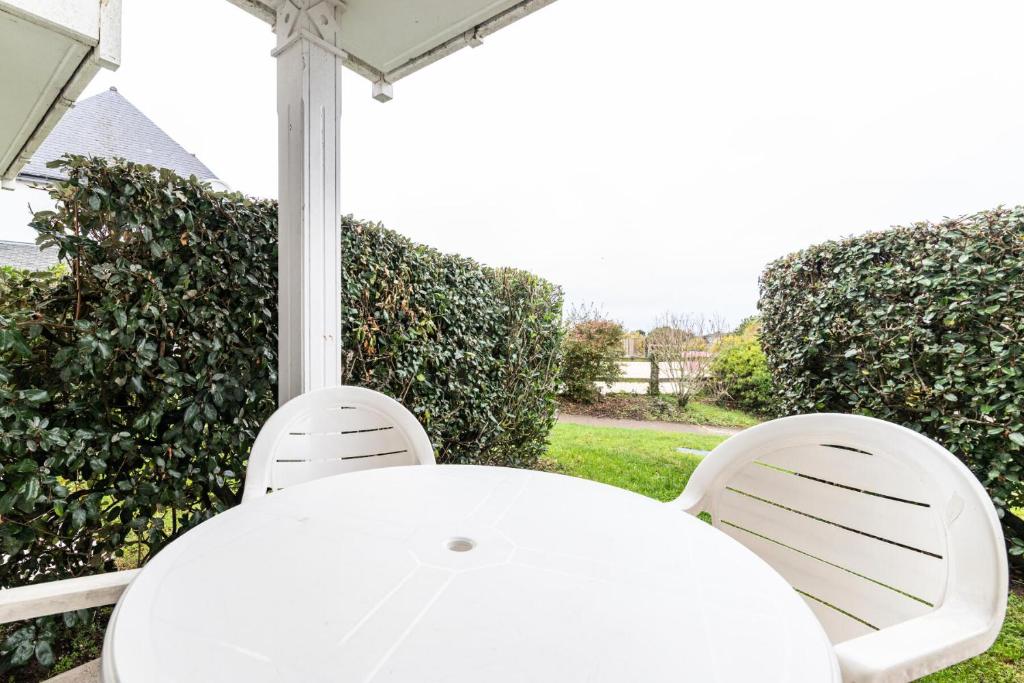 une table et des chaises blanches sous un parasol dans l'établissement Port du Crouesty Cap'Océan - maeva Home - Appartement 2 Pièces 4 Personnes - Sélection MAE-0784, à Arzon