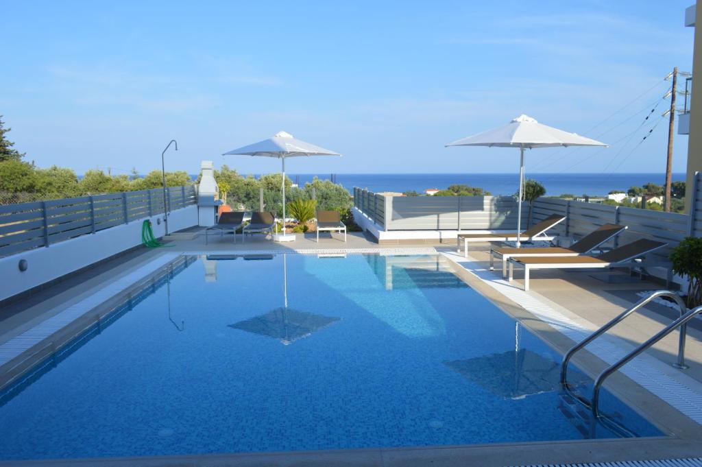una piscina con bancos y sombrillas en un edificio en Gennadi Aegean Horizon Villas, en Gennadi