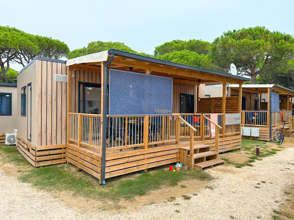 a large wooden cabin with a large screened porch at Estivo Premium Deluxe mobile homes on Camping Malibu Beach in Lido di Jesolo