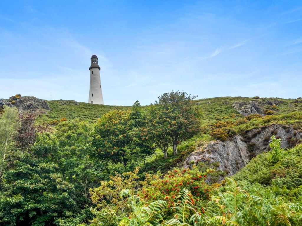 a lighthouse on top of a hill with trees at Pass the Keys Quaint Cottage Retreat in Charming Ulverston in Ulverston