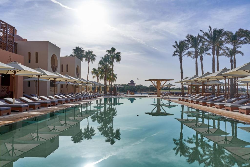 een zwembad met ligstoelen en palmbomen bij Steigenberger Golf Resort El Gouna in Hurghada