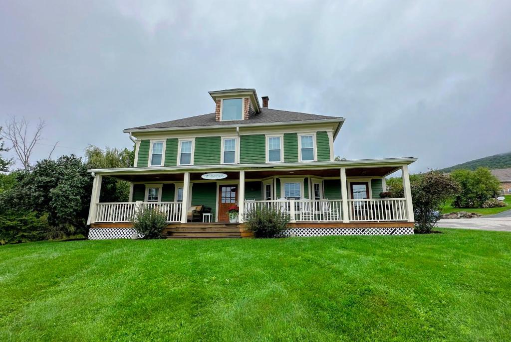 a green house with a porch and a lawn at 68CP Luxury farmhouse at the award-winning Bellevue Barn, 2 min to Santa's Village, AC, fireplace in Jefferson