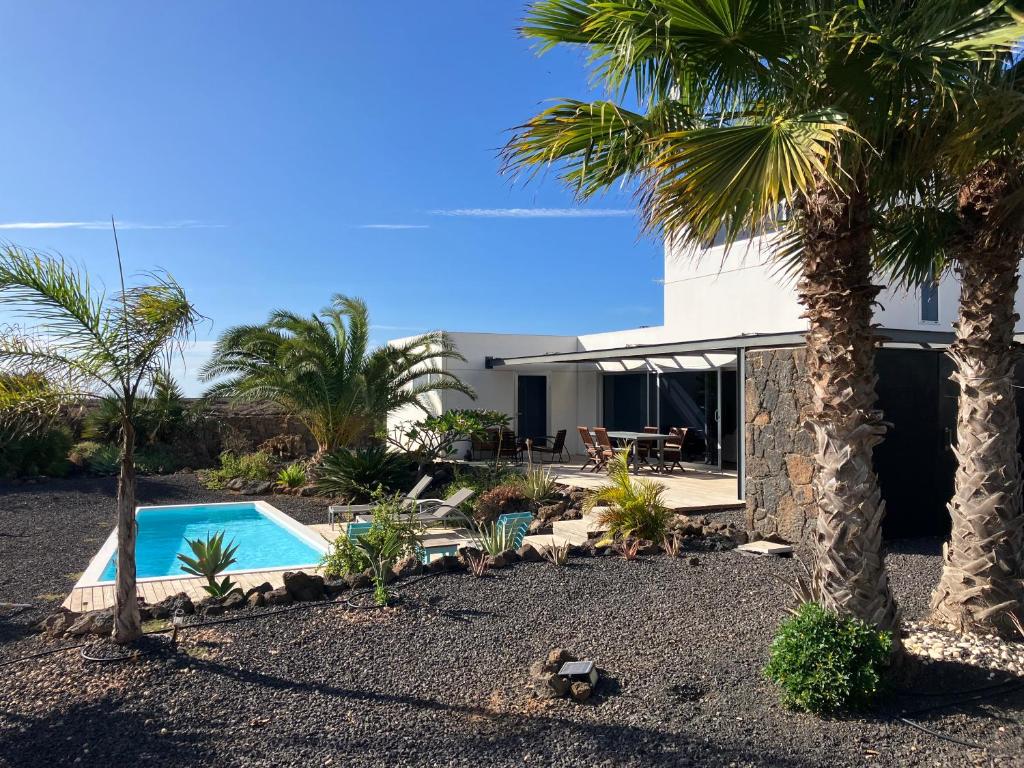 una casa con piscina y palmeras en Majanicho Rock - villa with heated pool, en Lajares