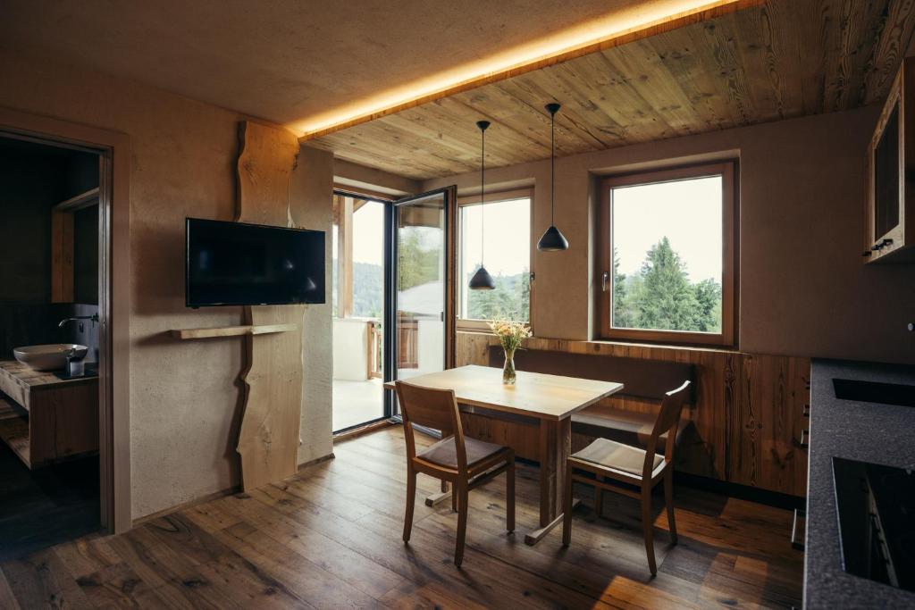 une salle à manger avec une table, des chaises et une télévision dans l'établissement Obertimpflerhof Wohnung Rosi, à Verano