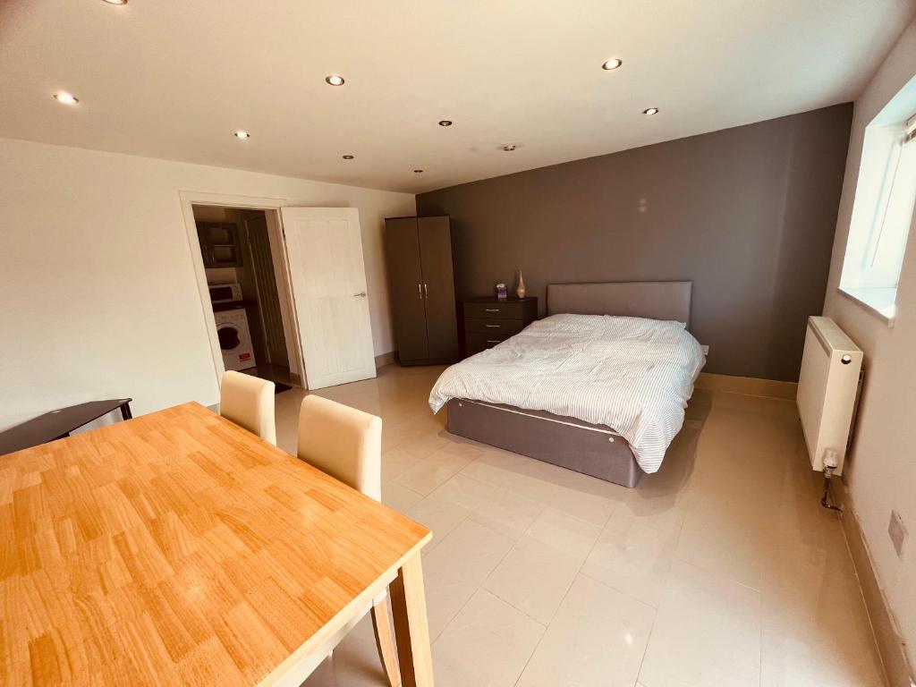 Large studio flat B near Heathrow في New Bedfont: غرفة نوم فيها سرير وطاولة فيها