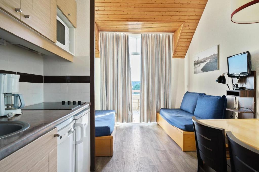 - une cuisine avec un canapé bleu dans une chambre dans l'établissement Résidence Port du Crouesty - maeva Home - Studio 5 Personnes - Confort - vue Mer MAE-0448, à Arzon