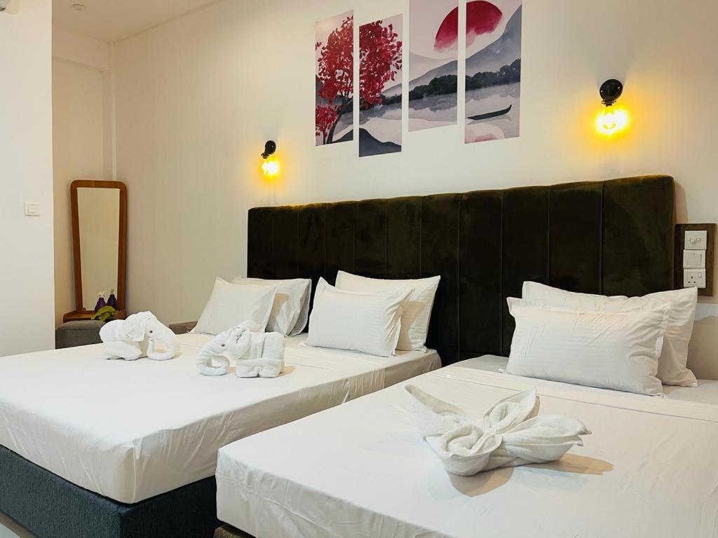- 2 lits avec des draps blancs et des chaussures blanches dans l'établissement Ismattha Hotel, à Anurâdhapura