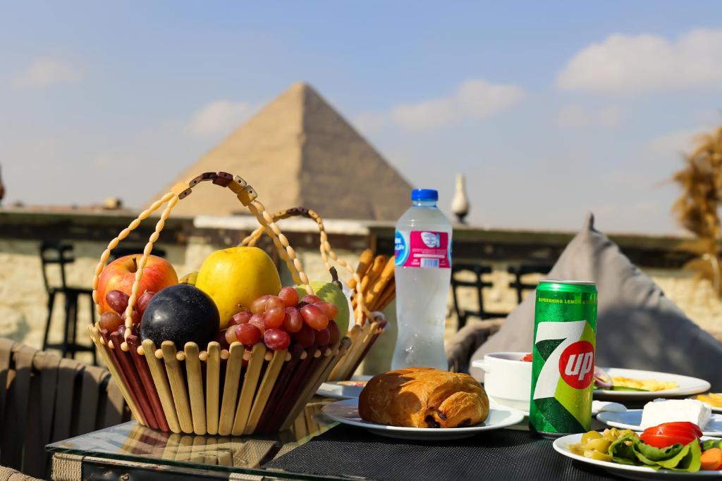 a table with a basket of fruit and bread with the pyramid at King Cheops Inn - Pyramid View in Cairo