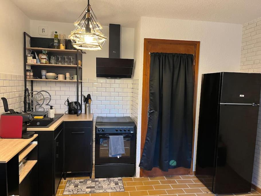 een keuken met een zwarte koelkast en een fornuis bij Lilaubaoli in Valdeblore