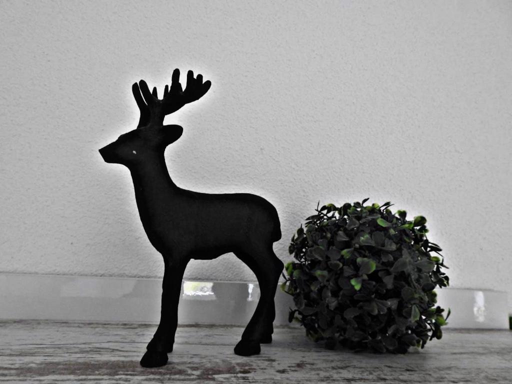 une statue d'un cerf à côté d'une plante dans l'établissement Appartement Balance, à Arzl im Pitztal