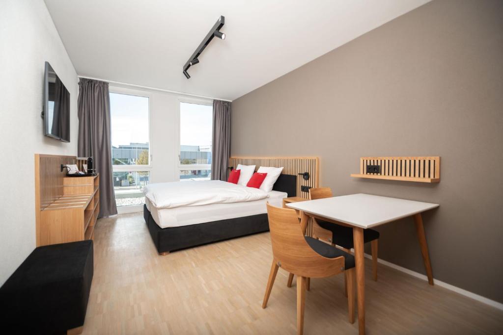 um quarto com uma cama, uma mesa e uma secretária em Tailormade Hotel BAB Bachenbülach em Bachenbülach