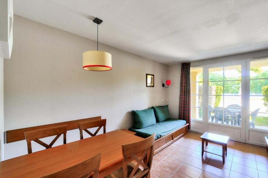 - une salle à manger avec une table et un canapé dans l'établissement La résidence du Lac - maeva Home - Appartement 2 pièces 5 personnes - Conf 454, à Monflanquin