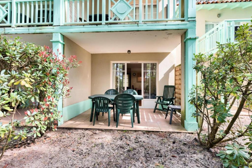 une terrasse avec une table et des chaises dans une maison dans l'établissement Résidence Lacanau Les Pins - maeva Home - Appartement 2 Pièces 5 Personnes - Prestige MAE-7327, à Lacanau