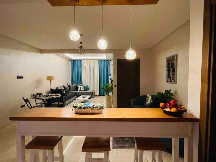 een keuken en een woonkamer met een grote houten tafel bij Appartement luxueux au centre de marrakech in Marrakesh