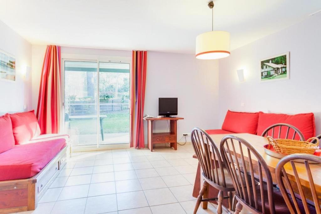 un salon avec un canapé rouge et une table dans l'établissement Village Moliets - maeva Home - 2 Pièces 5 Personnes Confort MAE-7861, à Moliets-et-Maa
