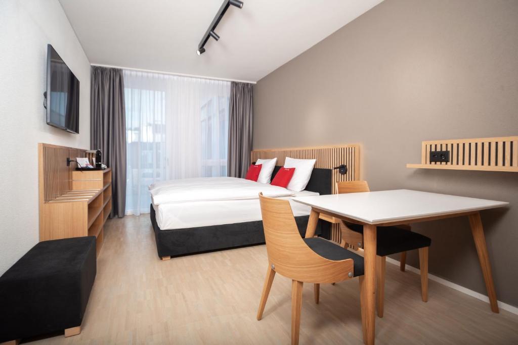 una camera da letto con un letto, una scrivania e un tavolo di Tailormade Hotel BAB Bachenbülach a Bachenbülach