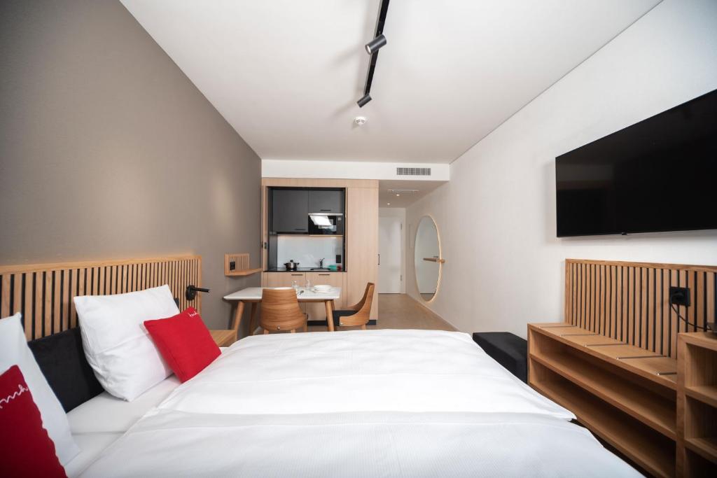 a bedroom with a large bed with a flat screen tv at Tailormade Hotel BAB Bachenbülach in Bachenbülach