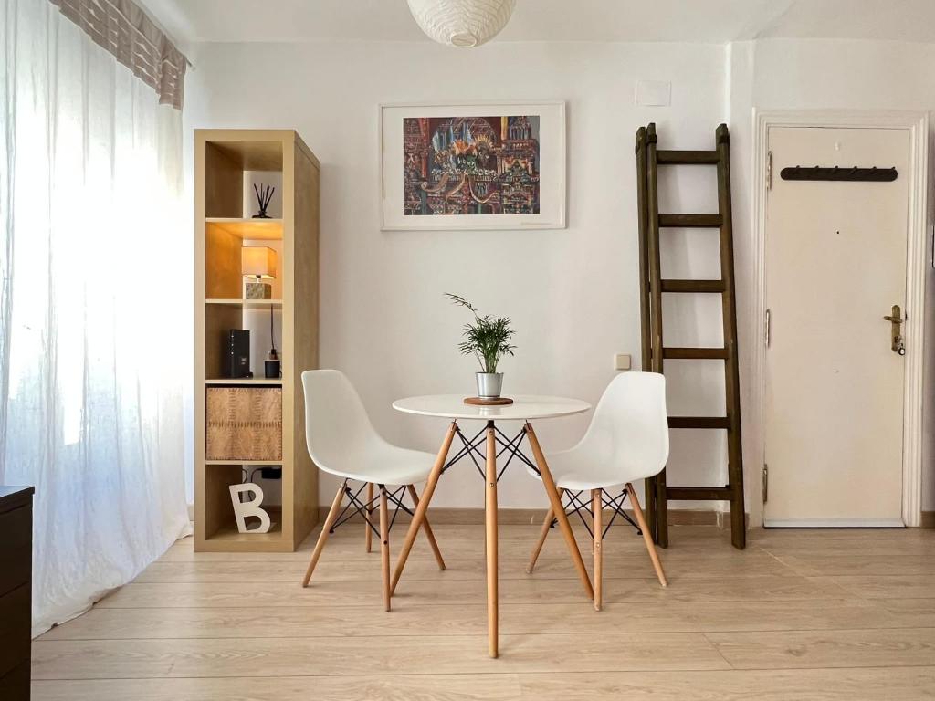 uma sala de jantar com uma mesa e cadeiras brancas em Lovely studio con balconcitos em Madri