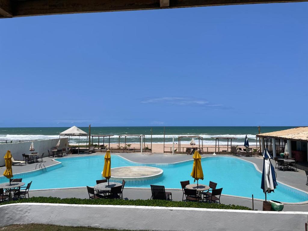 una piscina con sillas y sombrillas y la playa en IMPERIAL AREMBEPE BEACH, en Arembepe